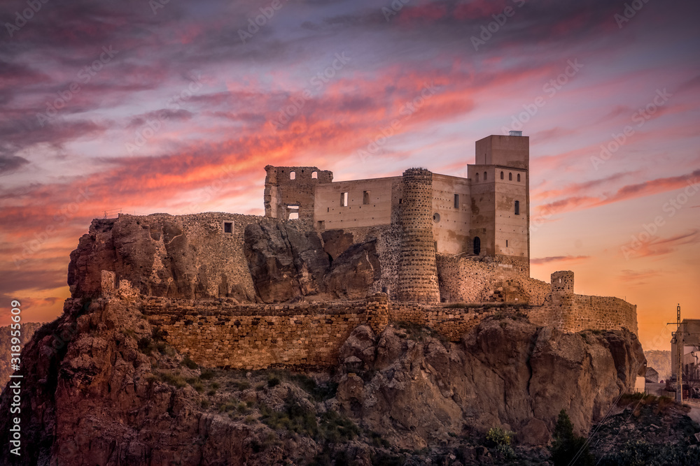 Aerial view of medieval partially restored Cofrentes castle above the Cabriel river in Spain with dramatic sunset sky