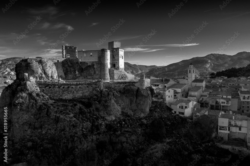 Aerial panoramic view of medieval partially restored Cofrentes castle above the Cabriel river in Spain with reflection and dramatic sky