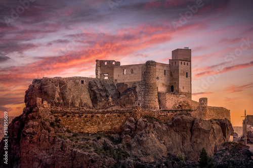 Aerial view of medieval partially restored Cofrentes castle above the Cabriel river in Spain with dramatic sunset sky
