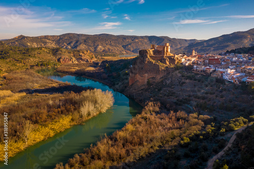 Aerial panoramic view of medieval partially restored Cofrentes castle above the Cabriel river in Spain with reflection