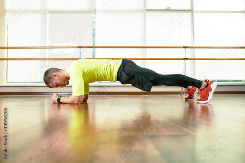 a man does an exercise plank in the hall on the floor opposite the window. Sports lifestyle, movement life.