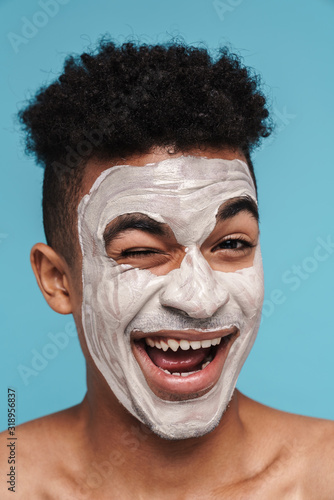 Photo of joyful african american man in facial mask smiling and winking