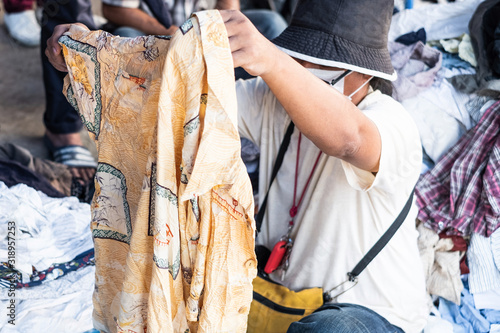 Thai man is choosing used second hand clothes at flea market in Thailand