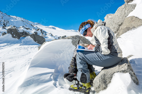 Obraz na płótnie Female mountaineer reading a guide book in the mountains to find a way. w salonie