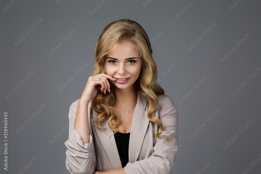 Portrait of happy curly business woman thinking about something on gray background Portrait of happy curly business woman thinking about something on gray background