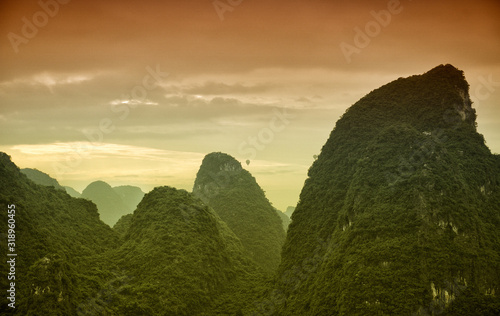 Hot air balloons flying over Karst mountain landscape in Chinese Guanxi province. photo