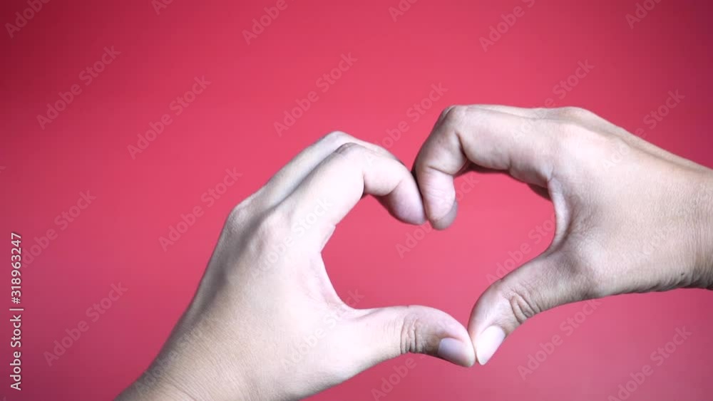 Zoom in hands making heart shape on red background. Zoom in hands making heart shape on red background.