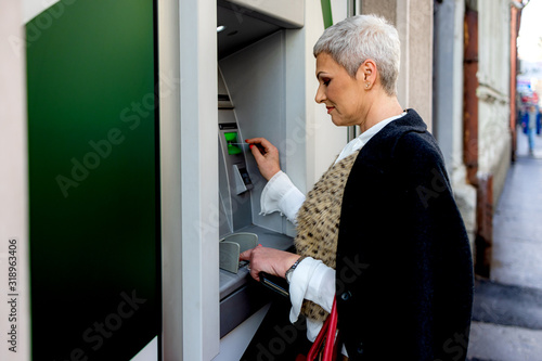 Middle age woman is withdrawing money from ATM machine