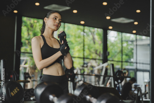 athletic young asian pretty slim body woman posing and looking her body in the mirror with machine in fitness gym, bodybuilder, healthy lifestyle, exercise fitness, workout and sport training concept