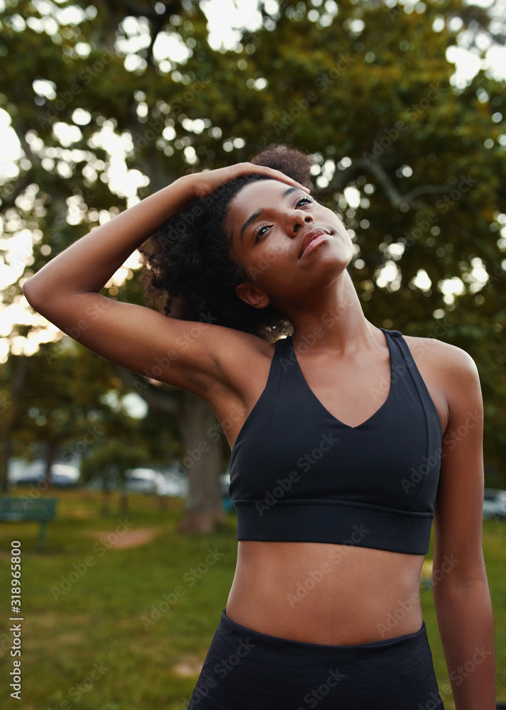 Portrait of an african american young woman stretching her neck while exercising in the park Portrait of an african american young woman stretching her neck while exercising in the park