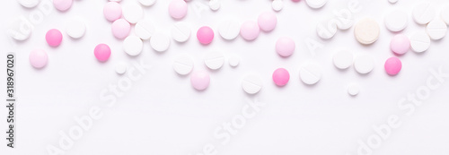 Pink and white pills on white background. Heap of assorted various medicine tablets and pills. Horizontal banner.