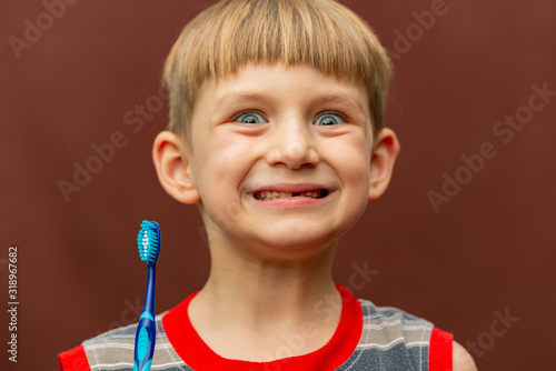 A smiling and joyful boy holds a toothbrush in his hand. photo