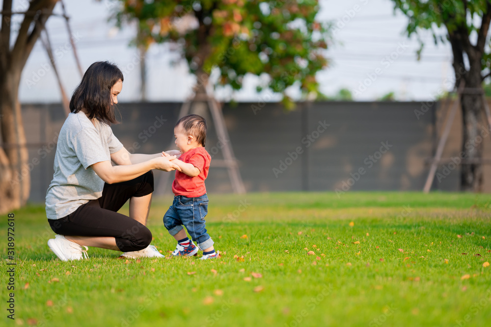 Cute baby scared to walk first steps with mother help at the park.The concept of baby development learning to walking.. Cute baby scared to walk first steps with mother help at the park.The concept of baby development learning to walking..