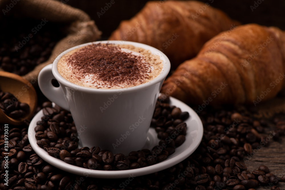 Fototapeta premium Cappuccino and croissant with coffee beans close up