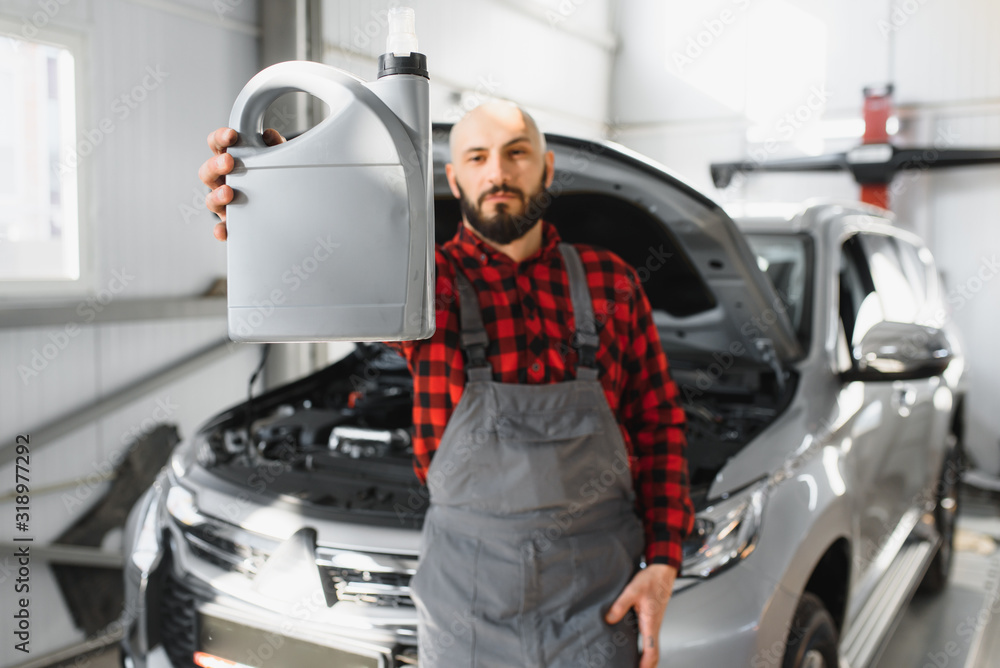 the car mechanic replaces the oil in the car. Car mechanic replacing and pouring fresh oil into engine car. the car mechanic replaces the oil in the car. Car mechanic replacing and pouring fresh oil into engine car.