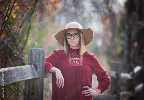Young Lady in Hat at Park against Fence