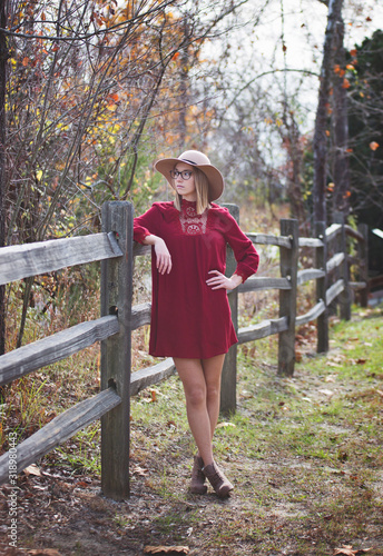 Young Lady In Hat At Park Against a Fence