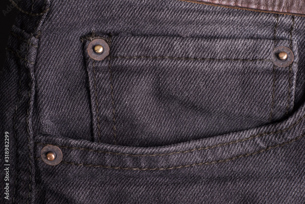 Large front pocket of black denim pants with a brown belt. Close-up Large front pocket of black denim pants with a brown belt. Close-up