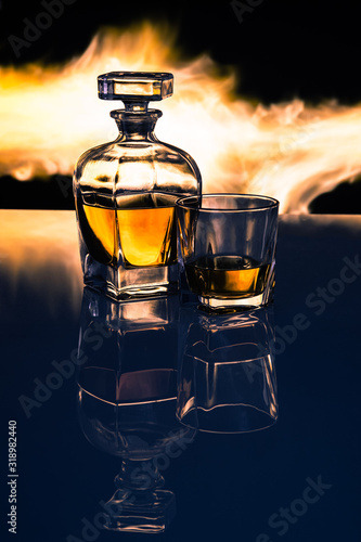 Karafka z whisky oraz szklanka na tle płomieni ognia, efekt odbicia