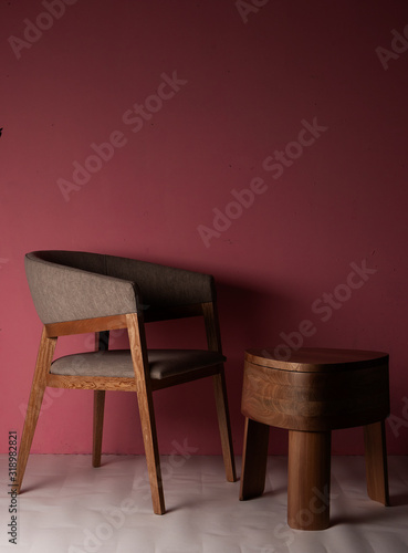 Silla de madera de lujo con mesa de madera pulida con tres patas en un espacio con pared rosada y piso en colores crema con luz de la maana photo