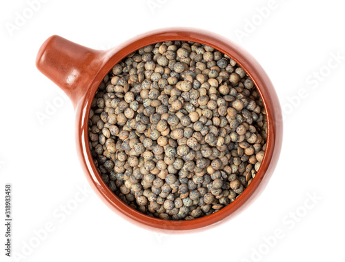 French green lentils in a ceramic bowl isolated on white background top view