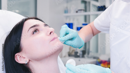 Beautician hands making botox injection in female lips. The doctor cosmetologist makes lip augmentation procedure.