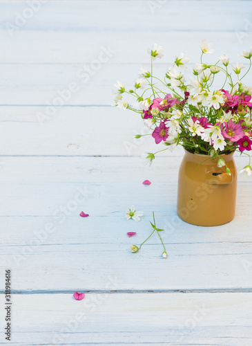 Wildflowers. Bouquet of white and pink flowers on a light blue shabby wooden background. Vintage floral background with wild flowers. Copy space © AllNikArt