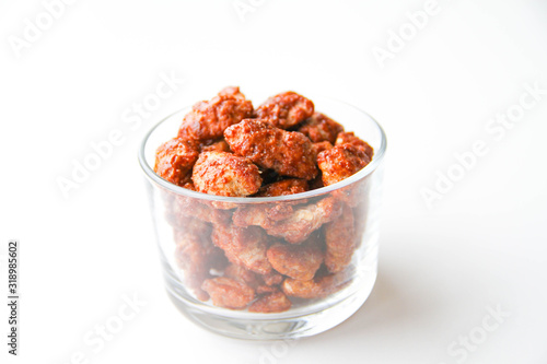 Sugar roasted pecan nuts (caramelized, praline nuts) in a glass on a white background, back view