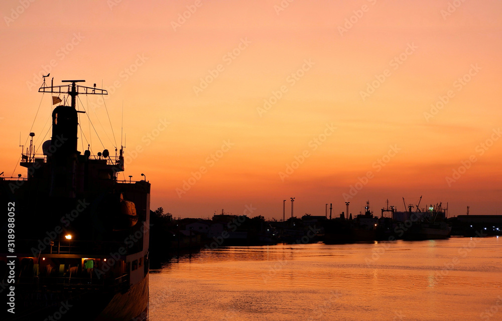 Silhouette cargo ship docked at port on the long and curved coast with ...