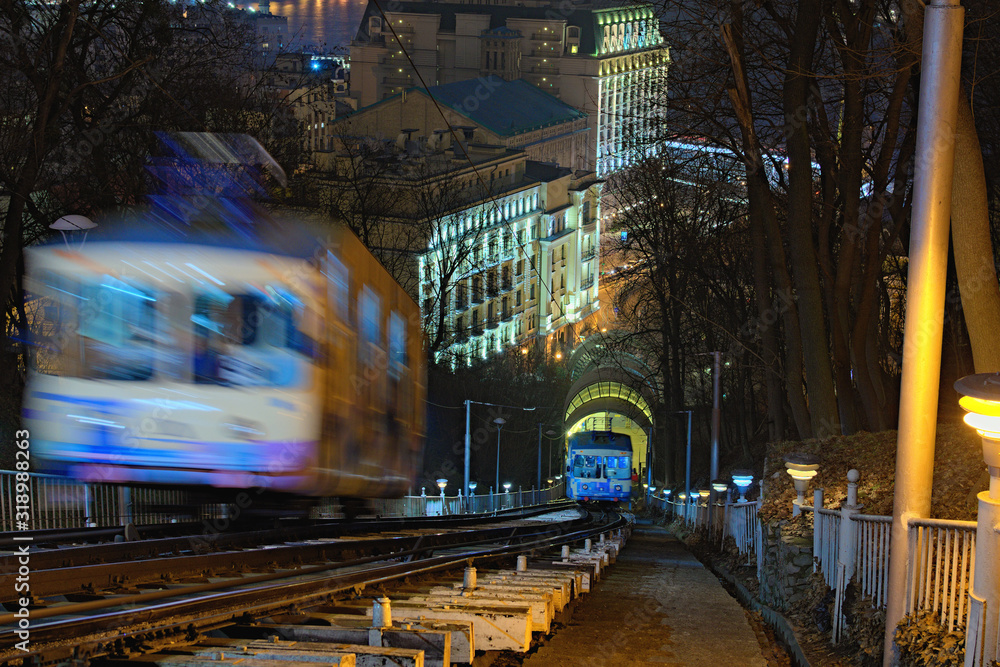 Kyiv, Ukraine-January 18, 2020: Cabins of funicular in motion, blurred view. Left coach goings to the upper station. Right car is almost near to the lower station. Night landscape of the city