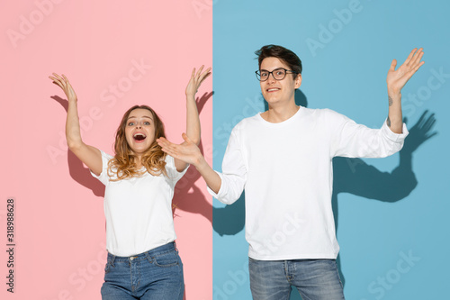 Shocked, astonished crazy. Young and happy man and woman in casual clothes on pink, blue bicolored background. Concept of human emotions, facial expession, relations, ad. Beautiful caucasian couple.