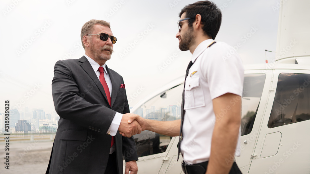Senior professional businessman shaking hand with the pilot before or after the trip with confidence face, while businessman taking the helicopter to the meeting or business trip. Senior professional businessman shaking hand with the pilot before or after the trip with confidence face, while businessman taking the helicopter to the meeting or business trip.