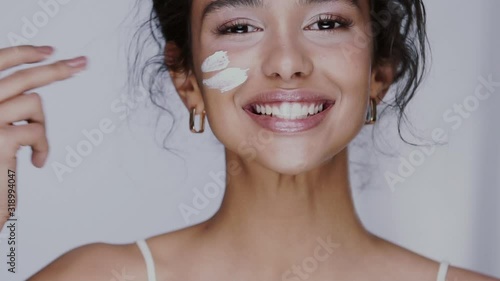 happy woman putting cream on her chick and laughing to camera
