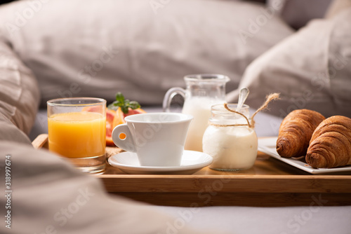 Continental breakfast. Breakfast tray on bed with coffee, orange juice and croissant