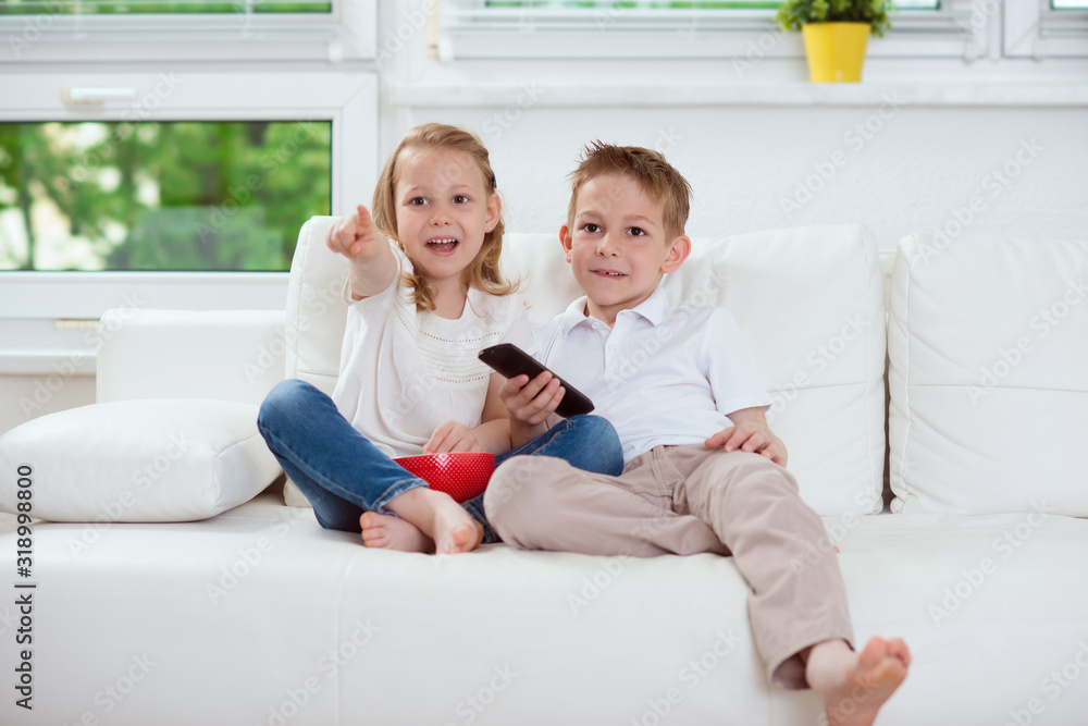 Little brother and sister watching tv on couch Little brother and sister watching tv on couch