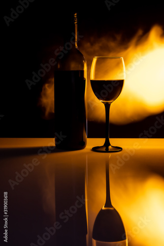 Butelka wina i kieliszek z płomieniami ognia z efektem odbicia