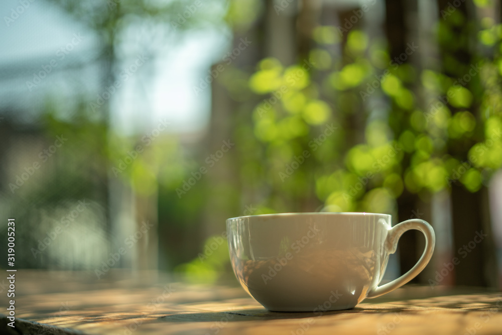 A cup of coffee on a wooden table in the morning. With copy space. and sunlight naturally a blurred background.