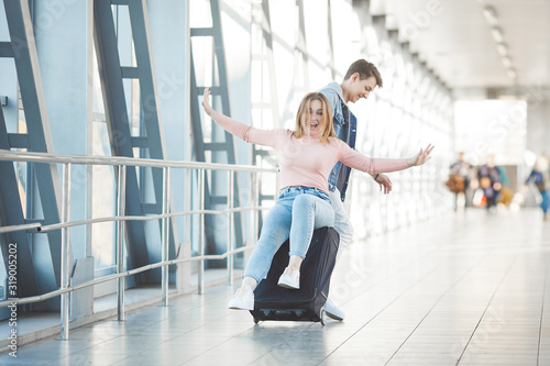 Happy young couple at the airport terminal having fun while waiting for their flight. Two people man and woman going to trip.