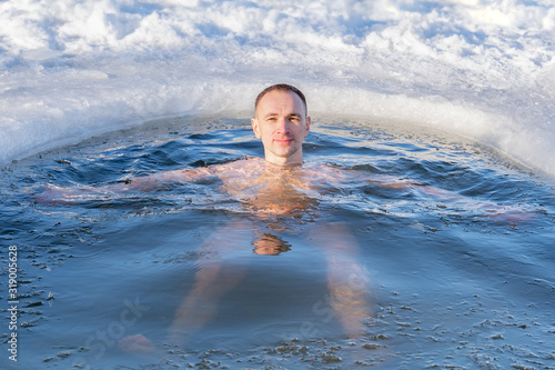 Portrait of a guy swimming in winter in the cold water of a lake  closeup