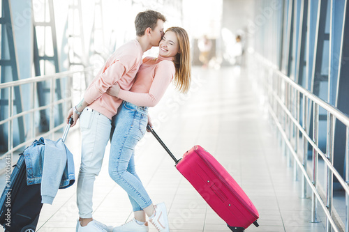 Happy young couple at the airport terminal having fun while waiting for their flight. Two people man and woman going to trip.