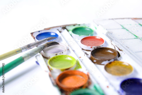 Used watercolor paint in box with two brushes, close-up isolated on white background. concept