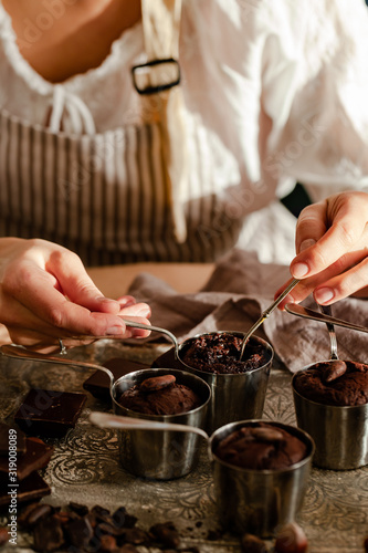 Young girl tasting delicious dark chocolate fondant cakes. Served in vintage ladles. Delicious elegant dessert for sweet-tooth, sweet breakfast. Romantic atmosphere, aromatherapy. Close up, macro
