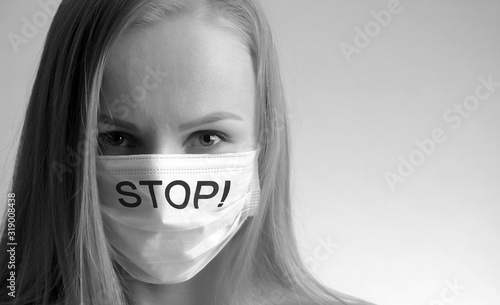 woman in a medical mask with the inscription stop close-up on a gray background. air pollution and deadly virus concept