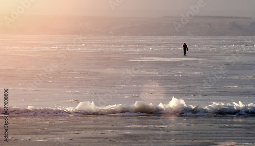 man on ice on a sunny frosty day. frozen lake or river and fisherman. danger of falling under water concept