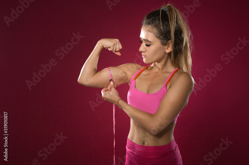 beautiful young woman in sportswear on a red background © Alexandr
