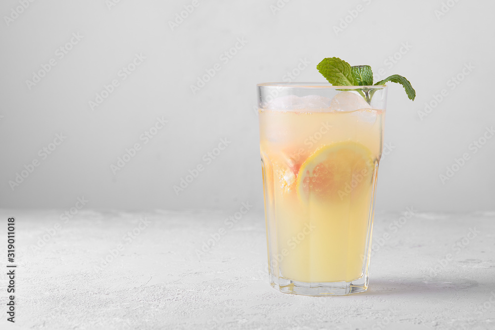 Summer refreshing lemonade with mint on a light background. A glass of citrus cocktail in a light key. Close up. Summer Vitamin cocktail of orange, lemon and grapefruit. Summer refreshing lemonade with mint on a light background. A glass of citrus cocktail in a light key. Close up. Summer Vitamin cocktail of orange, lemon and grapefruit.