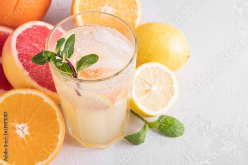 Summer refreshing lemonade with mint on a light background. A glass of citrus cocktail in a light key. Close up. Summer Vitamin cocktail of orange, lemon and grapefruit.