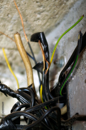 dangerous electrical power installations wires. hazard cables coming out from a wall photo