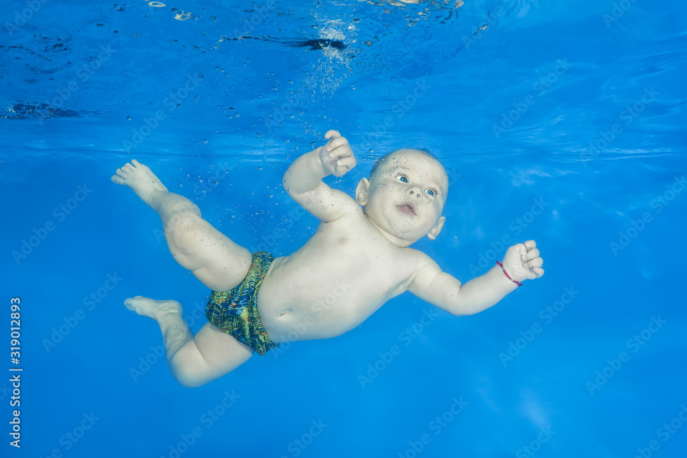 Little boy swim underwater in the swimming pool. Healthy family lifestyle and children water sports activity. Child development, disease prevention