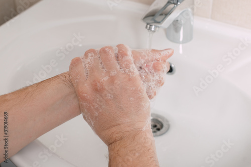 Hygiene concept. Washing hands with soap under the tap with water. handsome male hands and water in the bathroom.